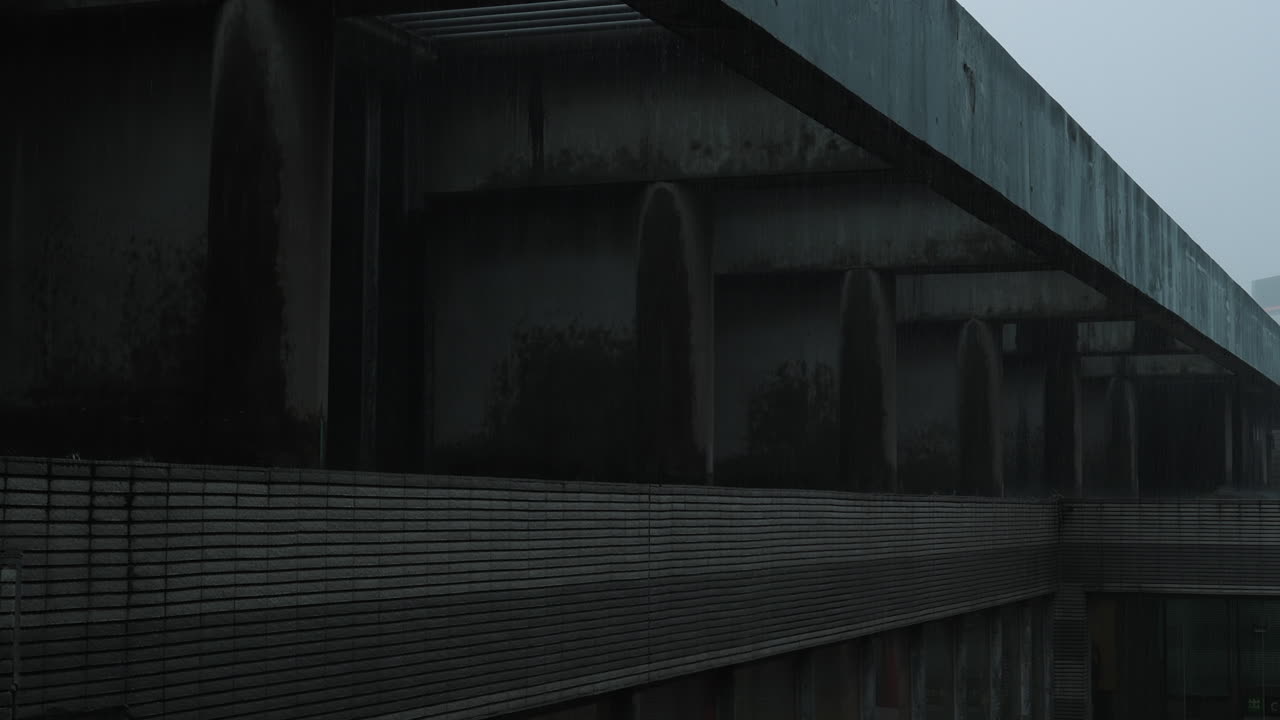 Rainwater runs down the textured side of a modern building