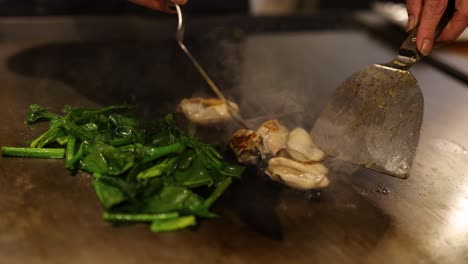 cooking oysters and greens on a hot wok