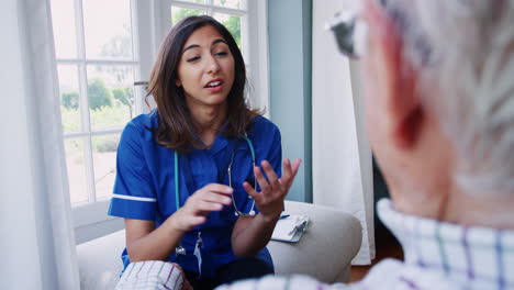 Over-shoulder-view-of-nurse-on-home-visit-with-senior-man