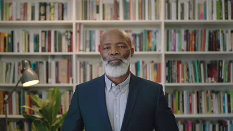 portrait of senior african american businessman with beard looking serious at camera wearing suit in library study successful black male executive