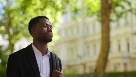 Young-Businessman-Wearing-Backpack-Walking-To-Work-In-Office-Along-Tree-Lined-Street-In-The-Financial-District-Of-The-City-Of-London-UK-1