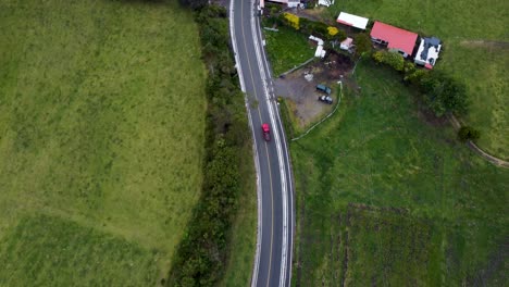 experimente la impresionante vista aérea de 4k mientras un avión no tripulado rastrea un coche a lo largo de una carretera sinuosa rodeada de una naturaleza exuberante