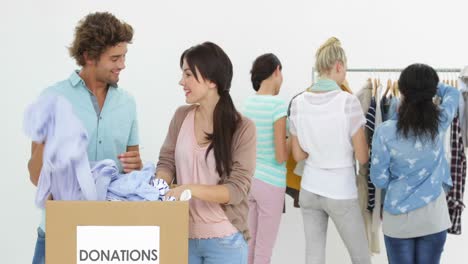 team of happy people going through donation box of clothes