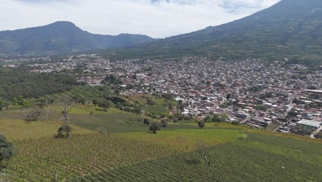 panoramic view of farmlands merging with a densely populated city at the base of a towering mountain in guatemala