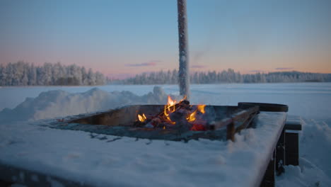 charred firewood logs burning in snowy frozen lapland outdoor campfire stove