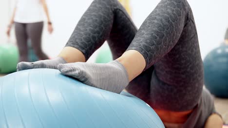 young women performing lying hip raise exercise with core stability using a physio exercise swiss ball in a sports physiotherapy clinic, close up