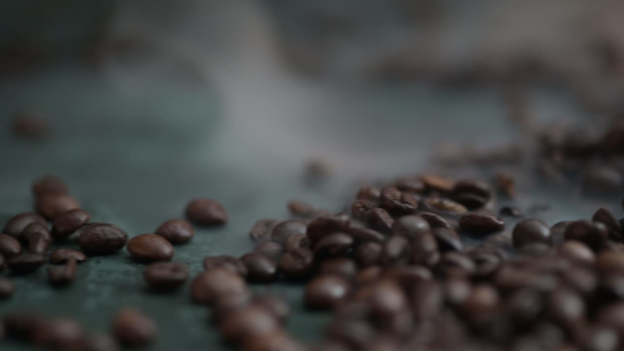 Dolly left of coffee beans lying on the dark green background surrounded by smoke
