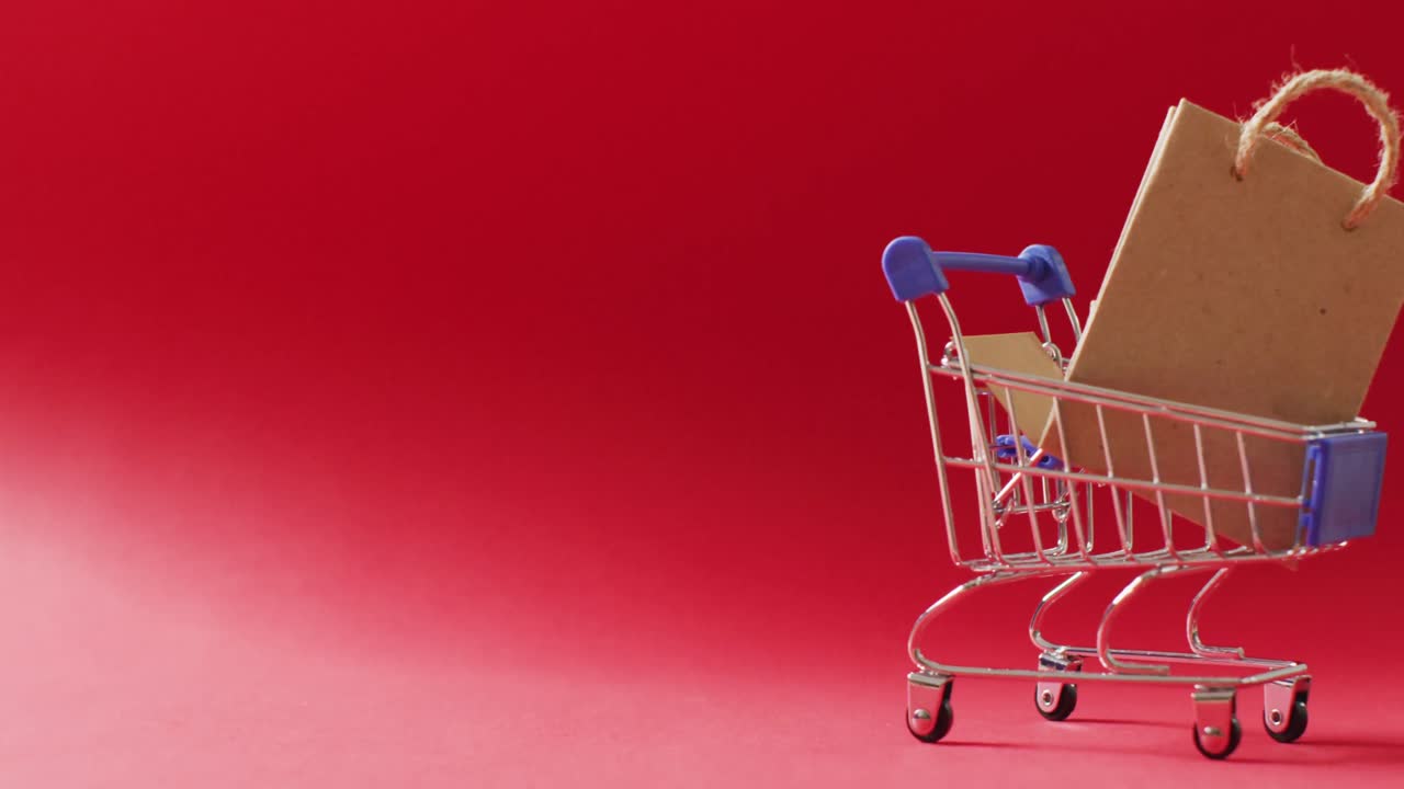 복사 공간과 함께  ⁇ 은 배경에 쇼핑 트롤리에서 갈색 선물 가방