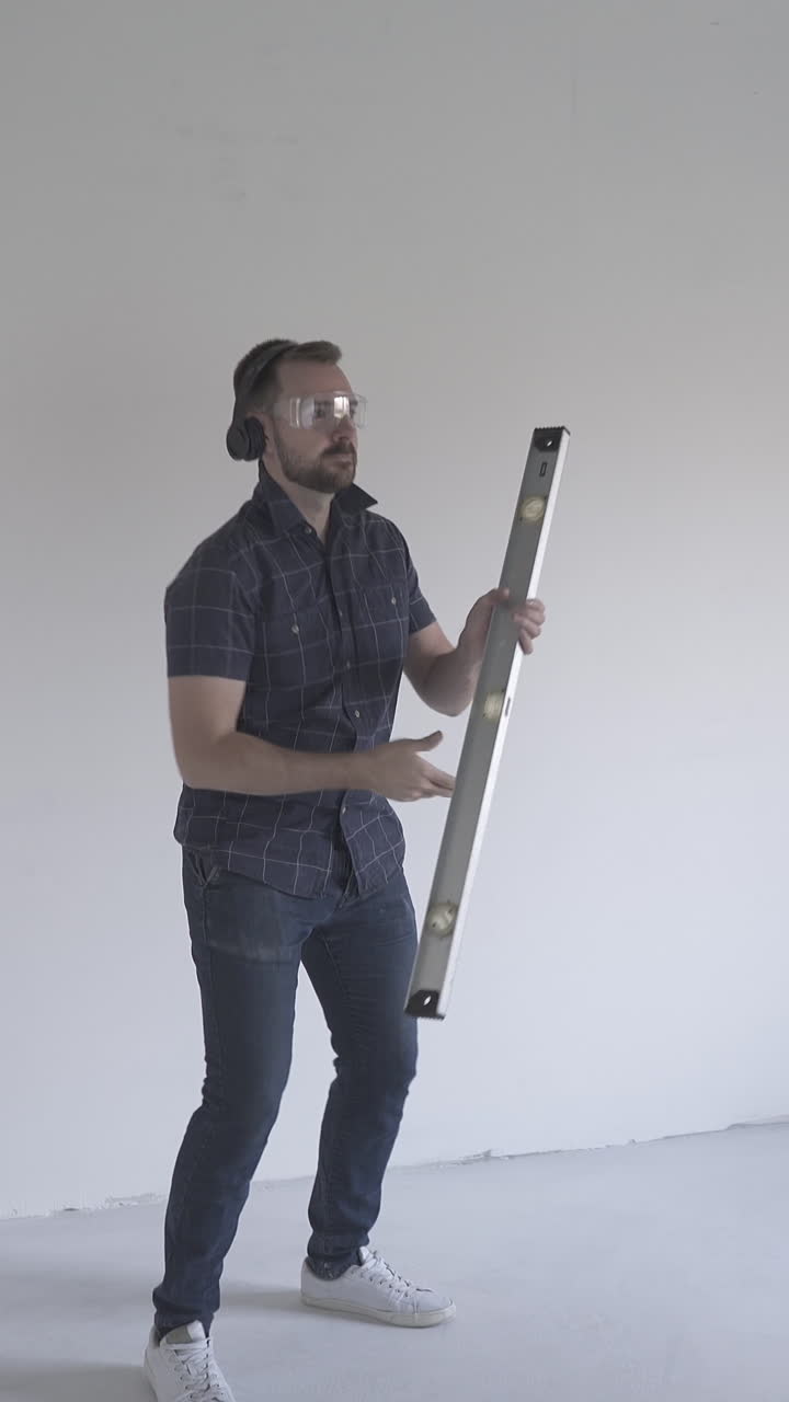 funny man turns professional level tool and pretty woman with phone has fun in renewing spacious flat with white walls