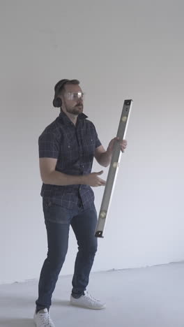 funny man turns professional level tool and pretty woman with phone has fun in renewing spacious flat with white walls