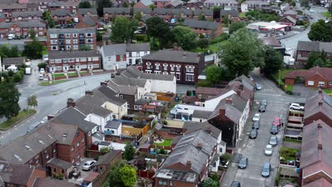 aerial view above british neighbourhood small town residential suburban property gardens and town streets fast right orbit