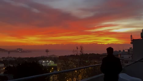 silhouette of business man standing on company terrace overlooking tagus river at sunset