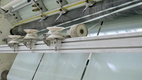 modern factory producing plastic foil and plastic bag. inside factory line. cellophane moves between the shafts. polyethylene bags.