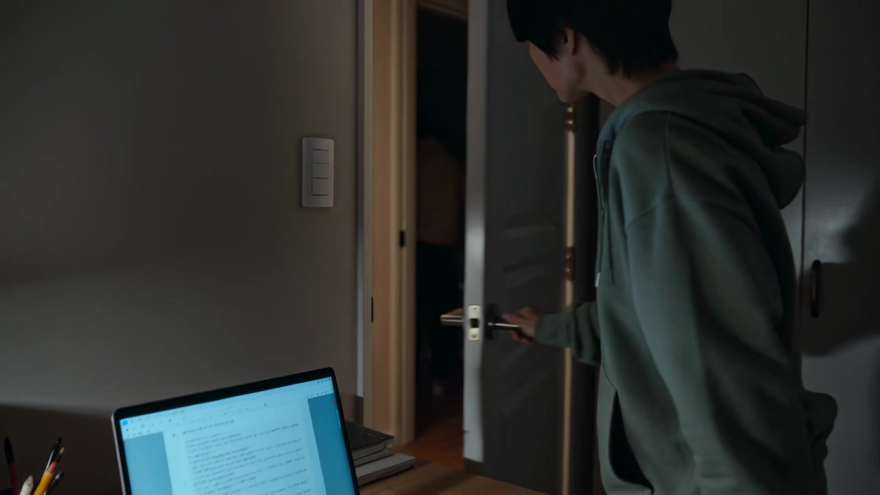 Noticing doorway movement Asian teen leaving laptop at desk opening door checking hallway in hoodie