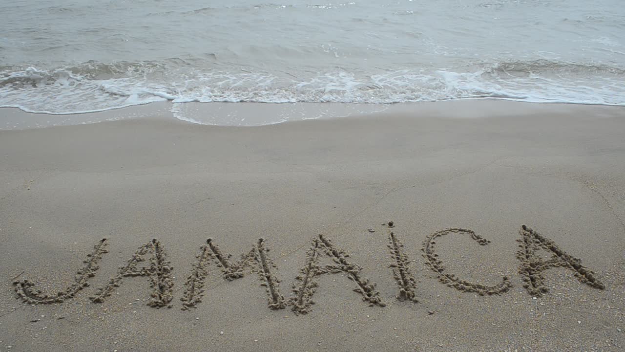 Tulisan Jamaika di pasir. Pemotretan di pantai