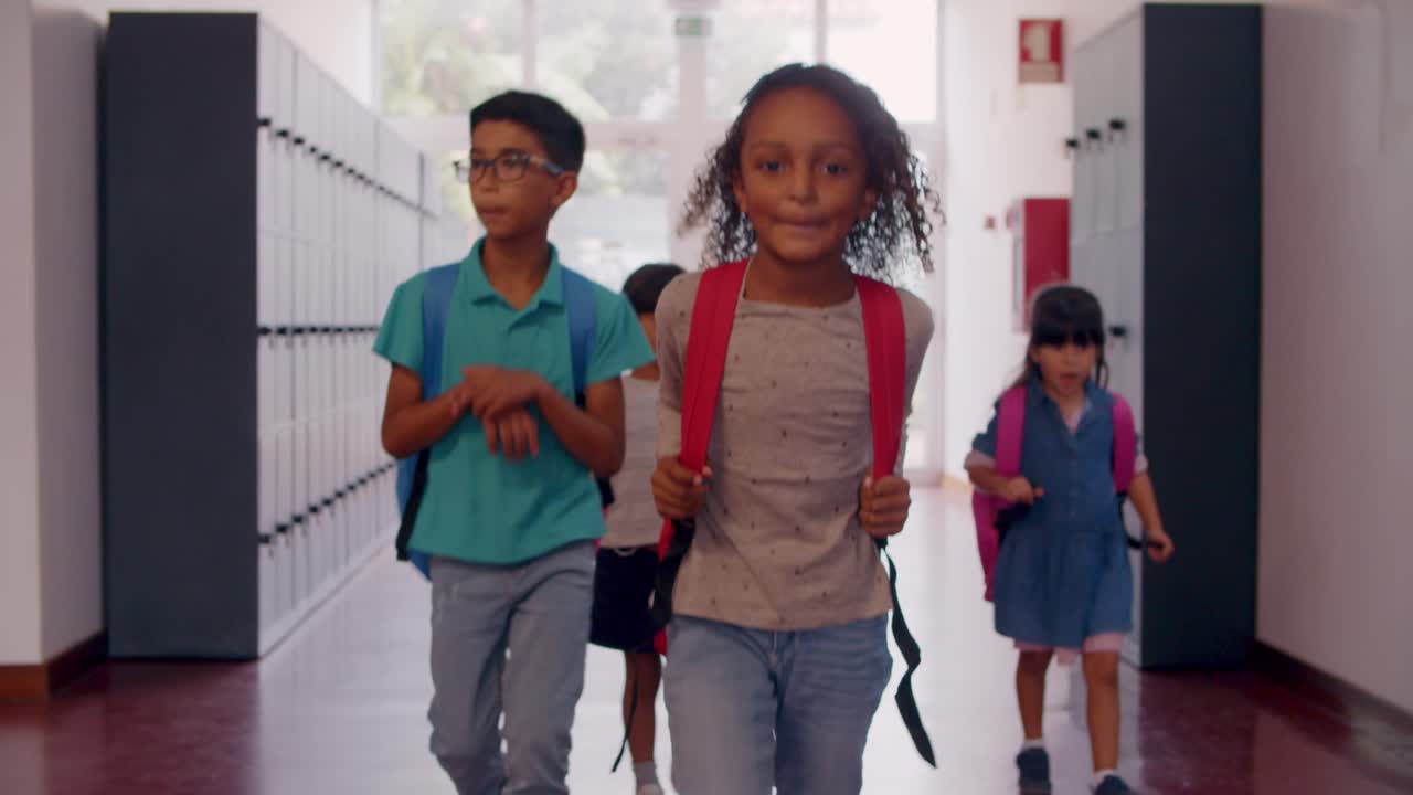 Front view of diverse group of schoolkids of different ages walking