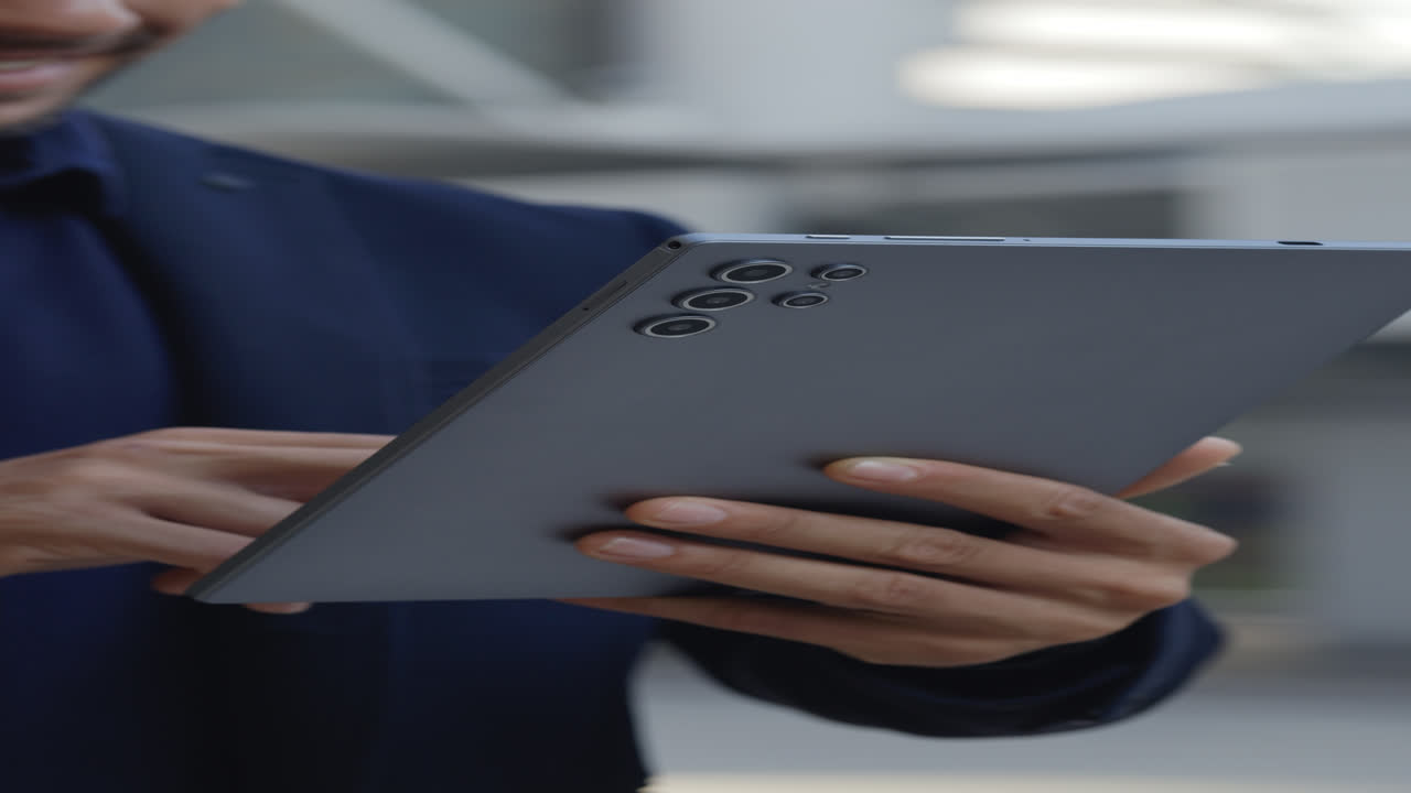 Person Holding and Pressing Buttons on a Modern Tablet