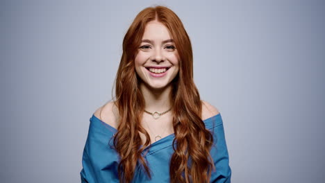 attractive girl looking at camera in studio. woman laughing on gray background