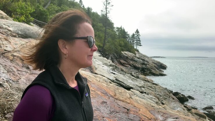 4K Lady Contemplates looking over Sand Beach in Acadia National Park near Bar Harbor Maine