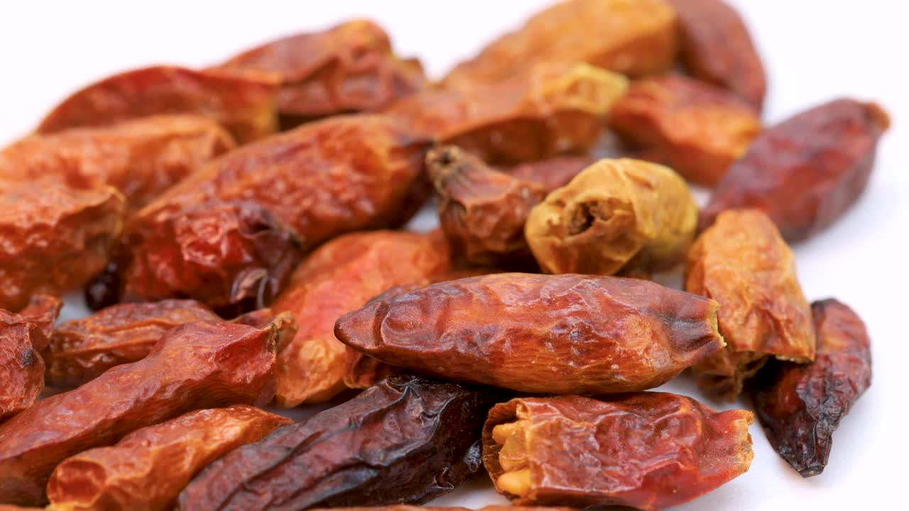 흰색 표면에서 회전하는 마른 카이엔 칠리의 클로즈업 뷰, 4k의 매크로 샷