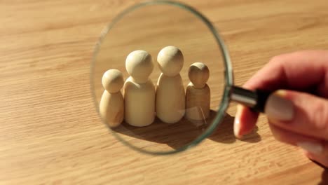 wooden family figures under a magnifying glass