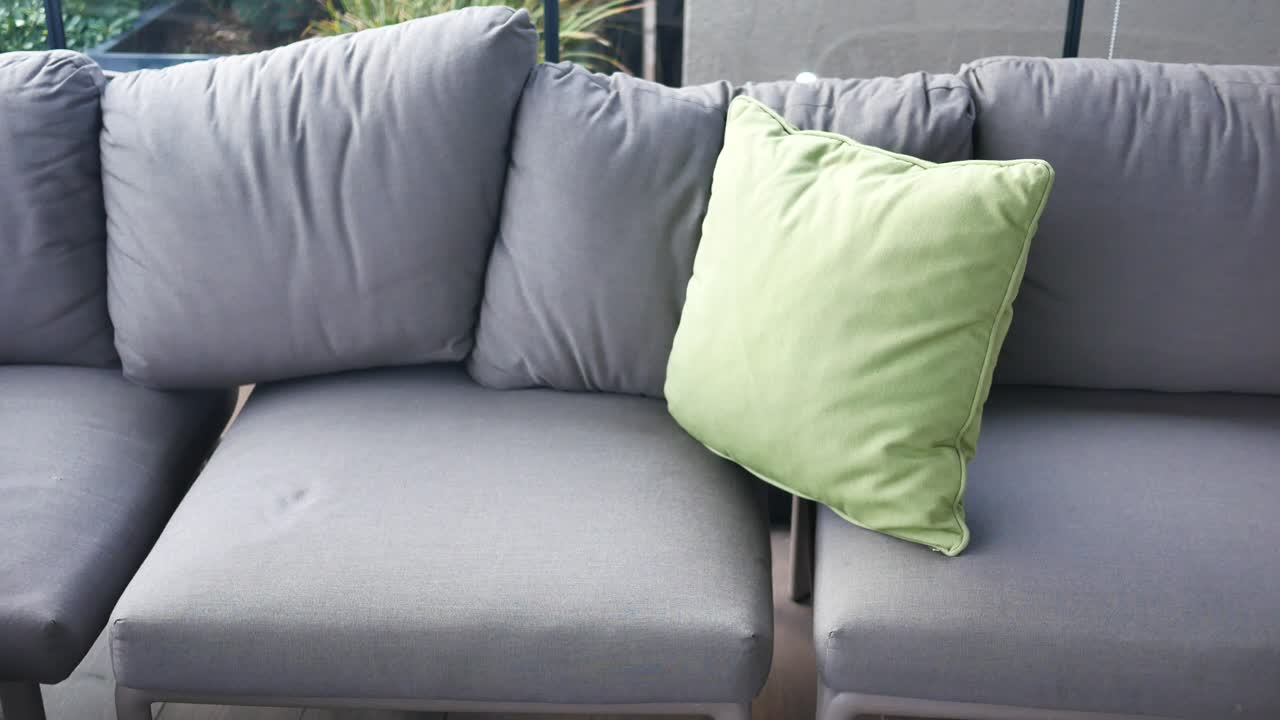 sofá al aire libre gris con almohadas verdes