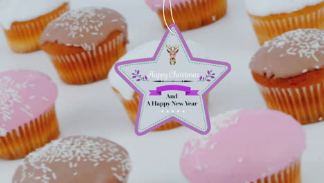 animation of christmas greetings on tag over cupcakes on white background