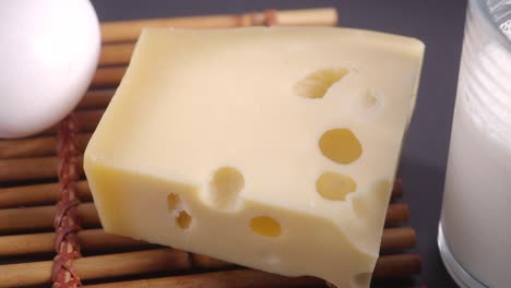 closeup of a piece of swiss cheese, a glass of milk, and an egg