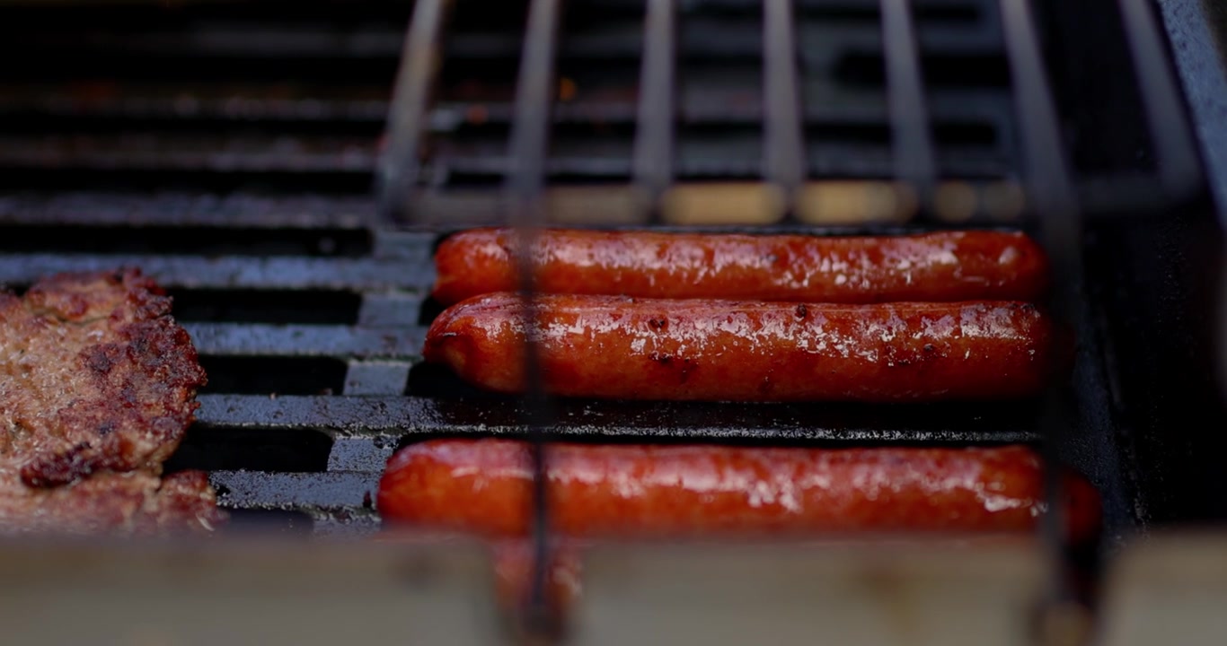 Barbecue del 4 luglio. Griglia nera che cucina carne, pollo, manzo, hot dog, cipolle in celebrazione del 250° compleanno degli Stati Uniti d'America. In Cinema 4K 30fps rallentato da 120fps