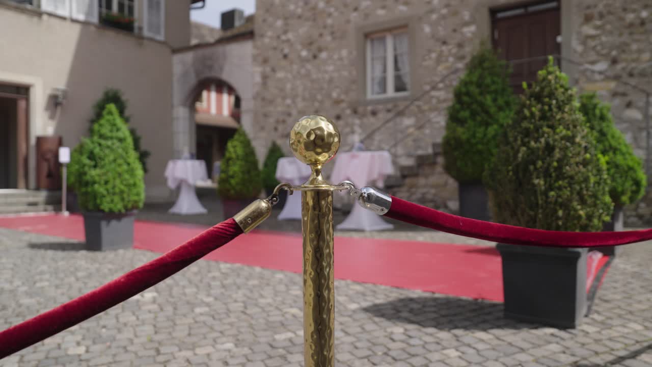 Elegant outdoor event entrance with red carpet and gold stanchions – wedding or gala setup