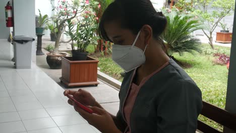 young asian woman using cellphone while sitting in the hall