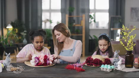 woman and girls decorating straw hats with flowers