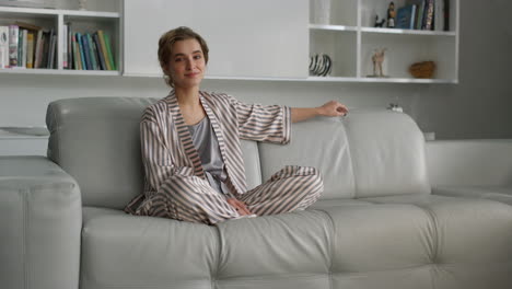 hermosa ama de casa posando en el sofá en pijama antes del desayuno. chica relajándose sola