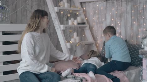 mother in sweater watches son and daughter play with toys