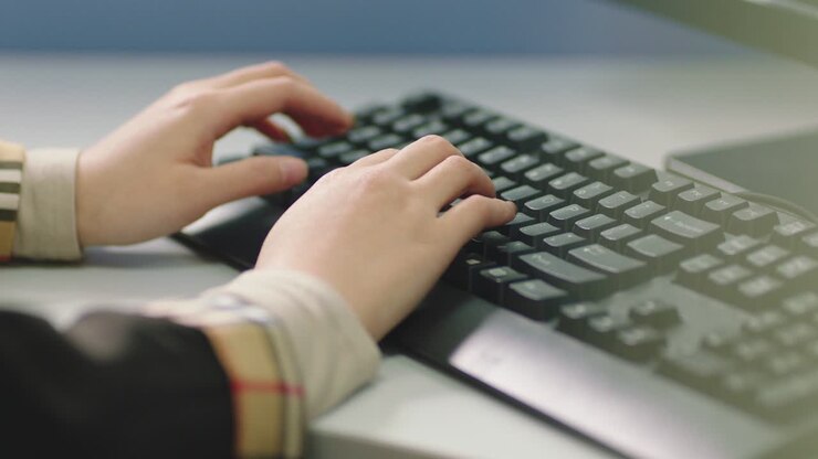 nahaufnahme des handtippens auf der computer-tastatur im büro