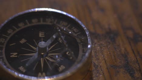 Tourist-Compass-Lying-On-The-Wooden-Table---Close-Up-Shot