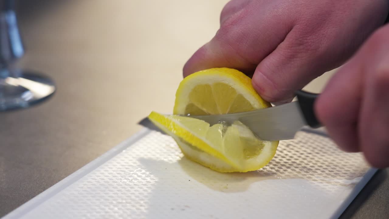 Hand slicing lemon on a white cutting board