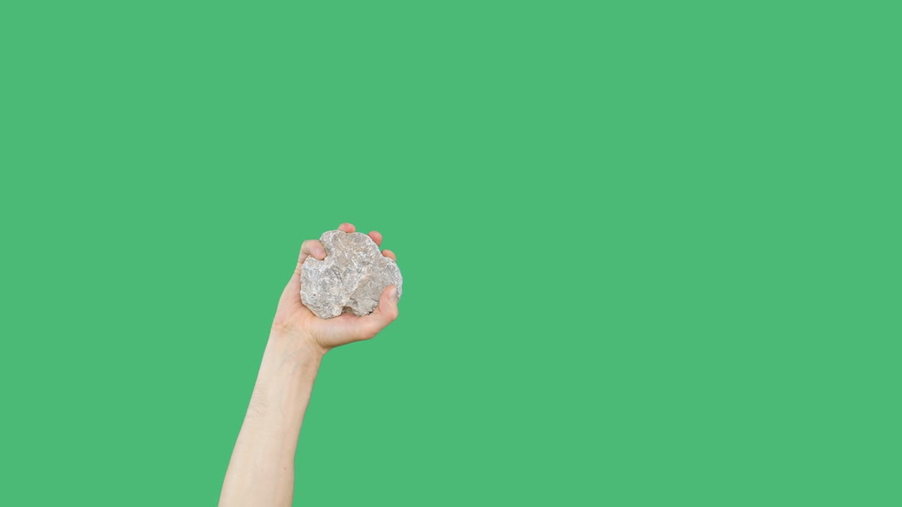 녹색 스크린 배경에 돌을 들고 있는 사람의 손. 녹색 스크로마키 배경에 있는 돌을 들며 들고 있는 인간의 손.