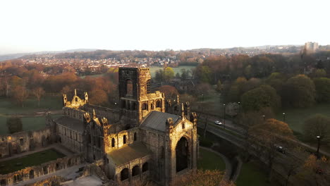 aerial pan of kirkstall abbey at dawn on sunny spring day with birds flying around