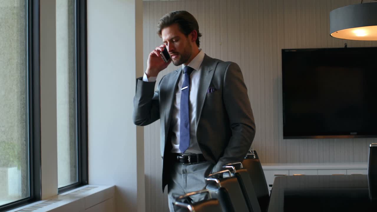 Uomo d'affari che parla al telefono cellulare in ufficio 4k