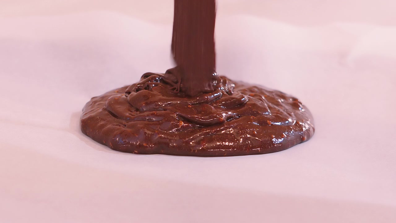 Versare l'impasto denso di brownie al cioccolato su carta da forno in una teglia. L'impasto denso e fondente si arriccia e si ripiega su se stesso mentre cade. Consistenza alimentare soddisfacente. 4K