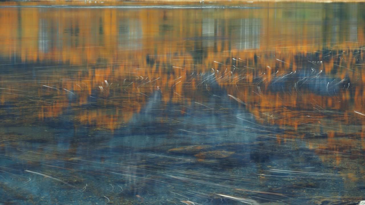 una mezcla de espuma y burbujas flota en la superficie del agua dejando rastros a medida que se mueve con la corriente