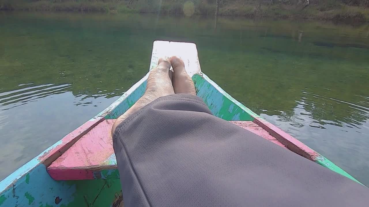 hombre relajándose en un barco de madera tradicional aislado en la orilla del río durante el día desde un ángulo plano