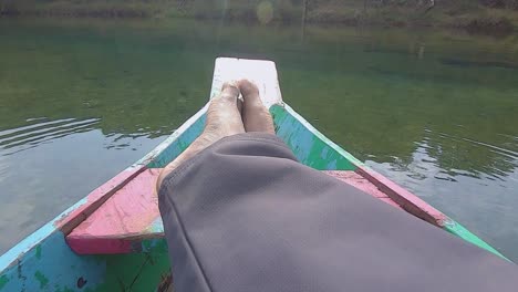 man relaxing at isolated traditional wood boat at river shore at day from flat angle