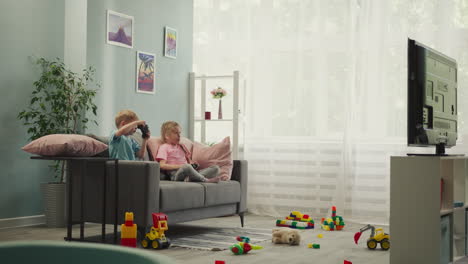 siblings play fun video game with consoles in living room