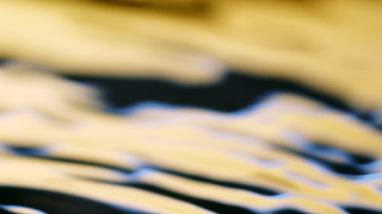 Water surface yellow and blue texture with clean ripples and wave refraction background. Slow motion
