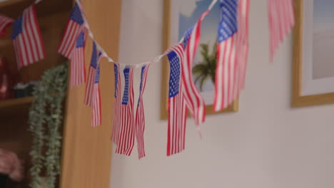 mujer en casa colgando estrellas americanas y rayas bandera bunting para la fiesta celebrando el 4 de julio día de la independencia 2