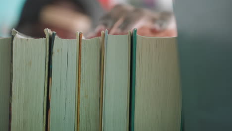 tight macro view of books on shelf as hand reaches to take one, page edges in focus, soft library bokeh beyond, quiet study moment capturing choice, search