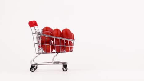 el carrito del supermercado se mueve lleno de tomates de cereza roja. aislado en el fondo blanco. primer plano. macro.