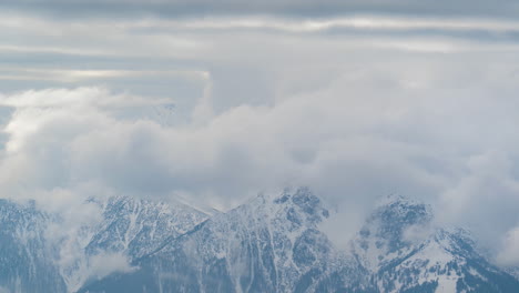 time lapse of clouds rising above snow capped peaks of austrian alps